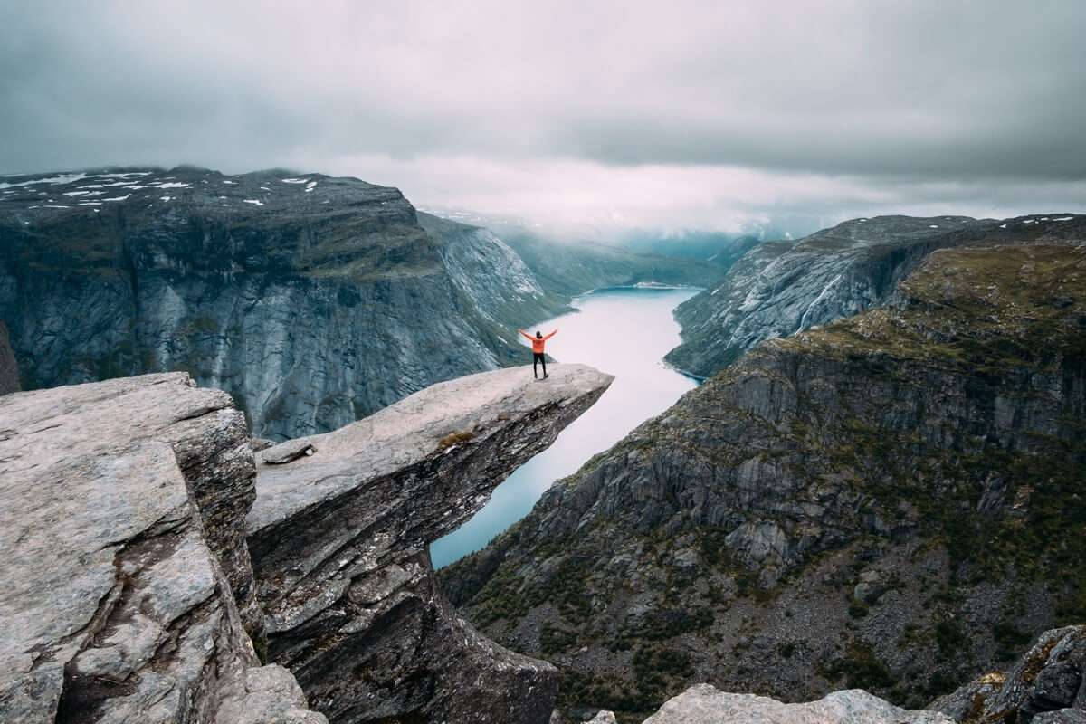 A man standing on a rock cliff overlooking a river